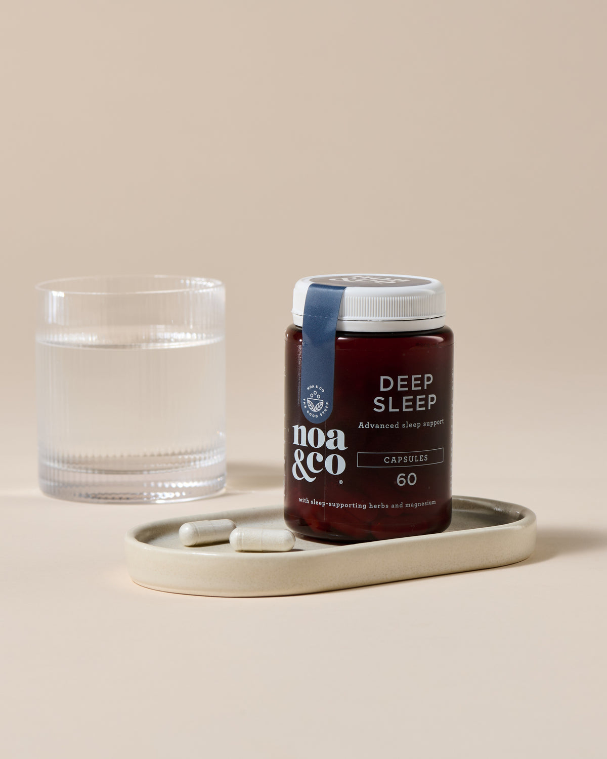 Noa & Co Deep Sleep Capsules, with a glass of water